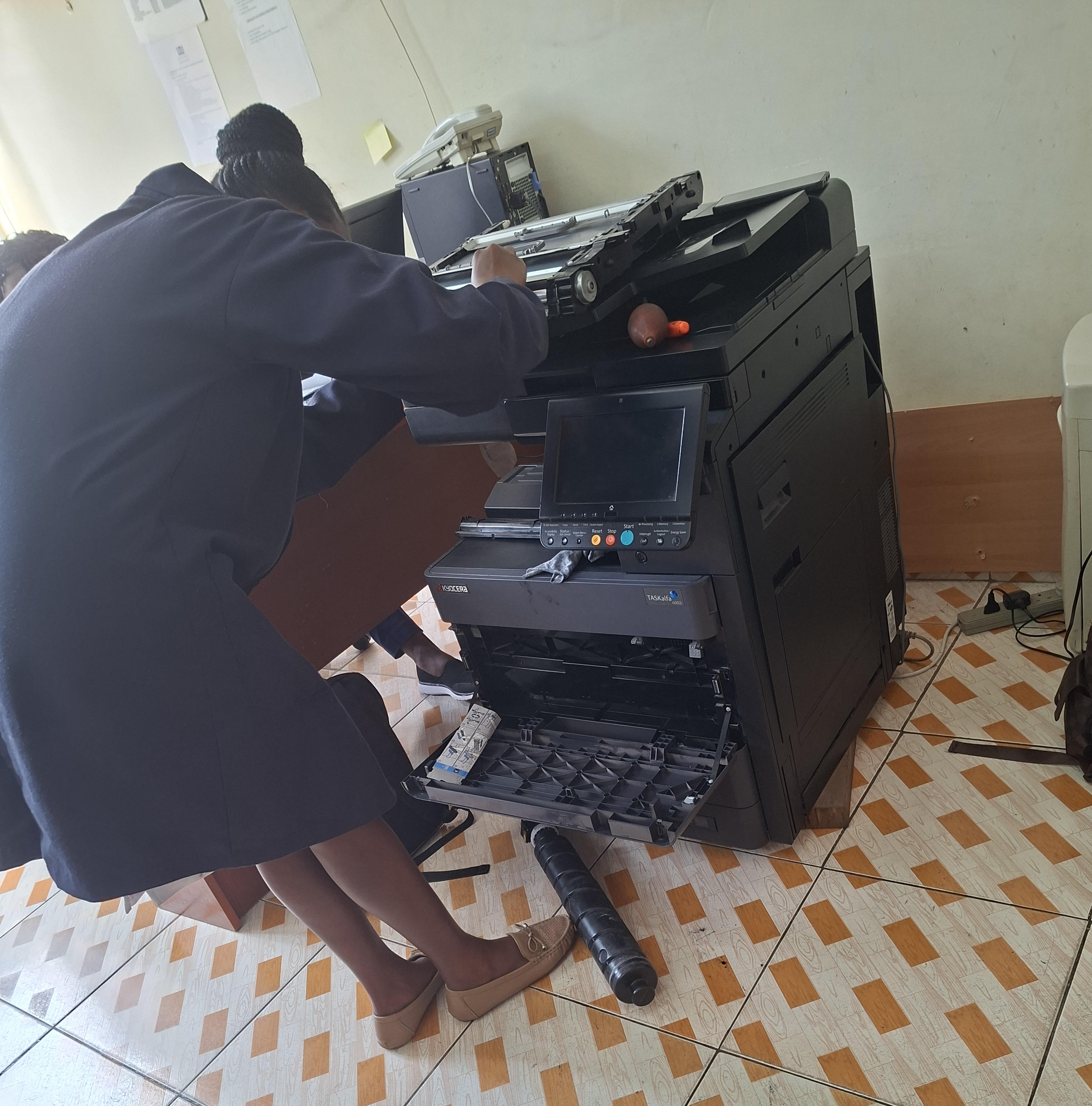 PrintFix Technologies certified technician performing on-site service on a Kyocera multifunction printer at a client office in Kenya